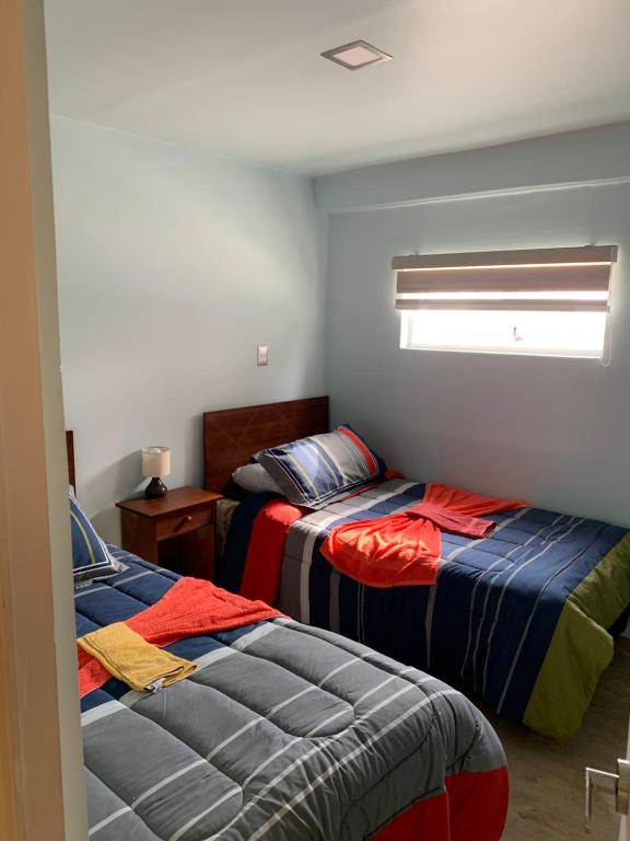 1 Schlafzimmer mit 2 Betten und einem Fenster in der Unterkunft Hostal Enerugi in Calama
