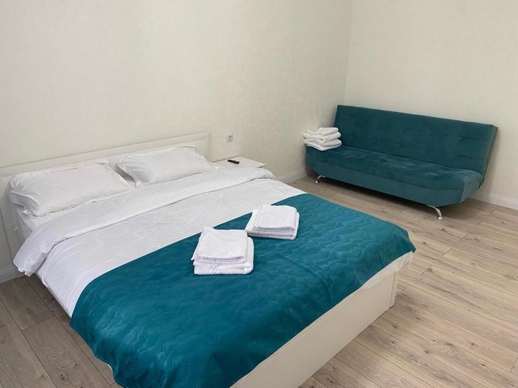 - une chambre avec un grand lit et un canapé bleu dans l'établissement Apartaments COSTA ЖК Тандау, à Astana
