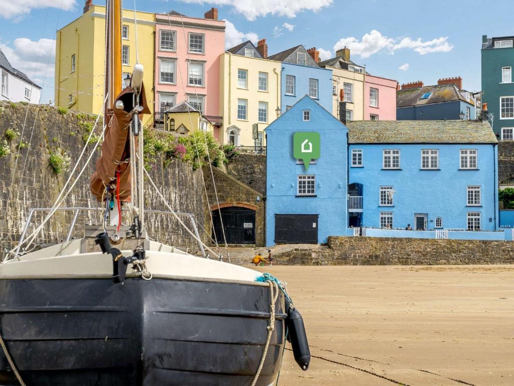 a boat sitting on the sand with buildings in the background at 2 Bed in Tenby 87912 in Tenby