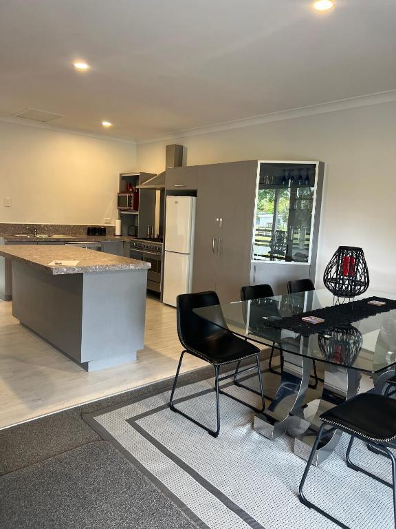 a kitchen with a glass table and black chairs at A Cut Above Lodge - The Gateway to the Bay of Islands in Kerikeri