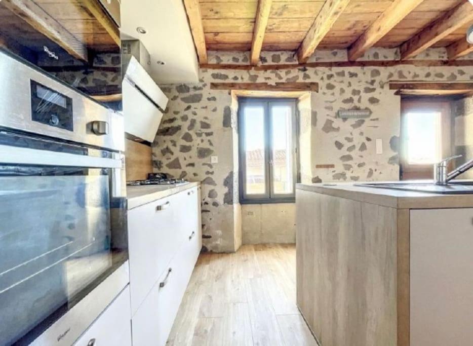 Il comprend une cuisine avec des appareils blancs et un plafond en bois. dans l'établissement Au coin des amis, à Aurillac
