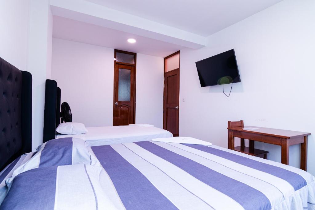 two beds in a room with a tv on the wall at Hotel Casa Nova jaen in Jaén