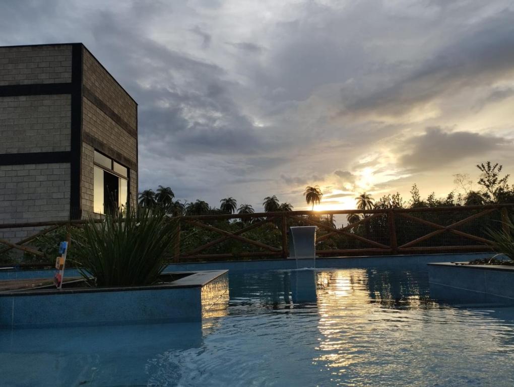 um edifício com uma piscina com o pôr-do-sol ao fundo em Pousada Quatro Estações em Santana do Riacho