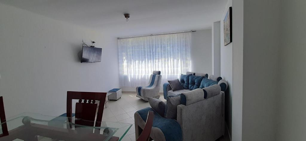 sala de estar con sillas azules y mesa de cristal en Apartamentos Turisticos EL ZIPA, en Zipaquirá