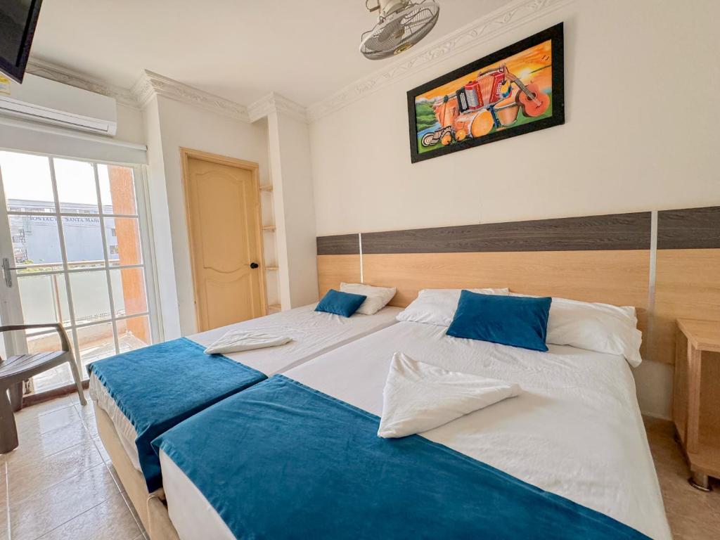 two beds in a bedroom with blue and white at Hotel Caribe Real Inn in Santa Marta
