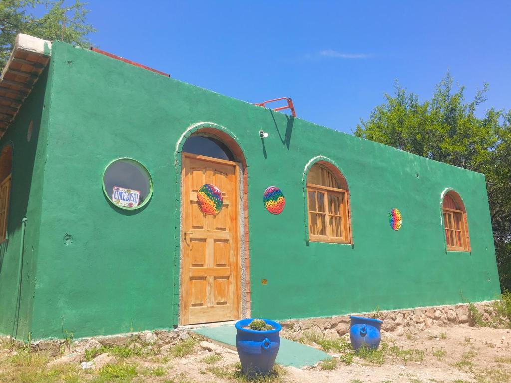 ein grünes Haus mit einer Tür und Fenstern in der Unterkunft Casa de montaña placentera en la naturaleza con vista espectacular en Traslasierra in Cordoba