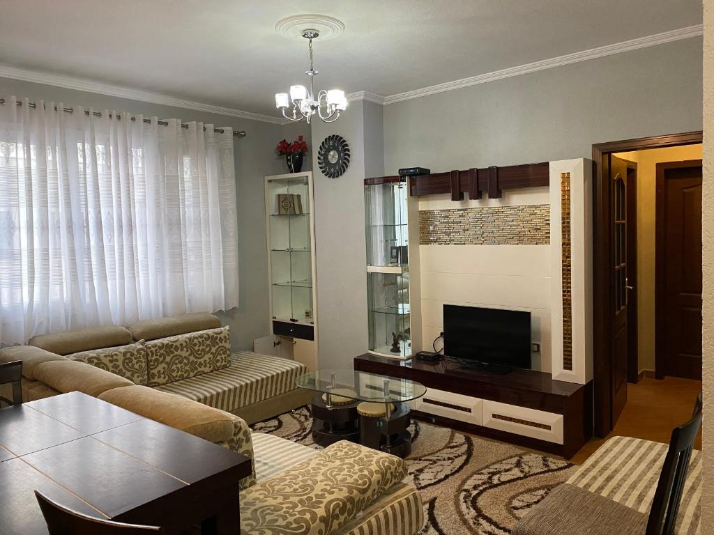 ein Wohnzimmer mit einem Sofa und einem TV in der Unterkunft Comfortable 2-BR for 5 in Tirana