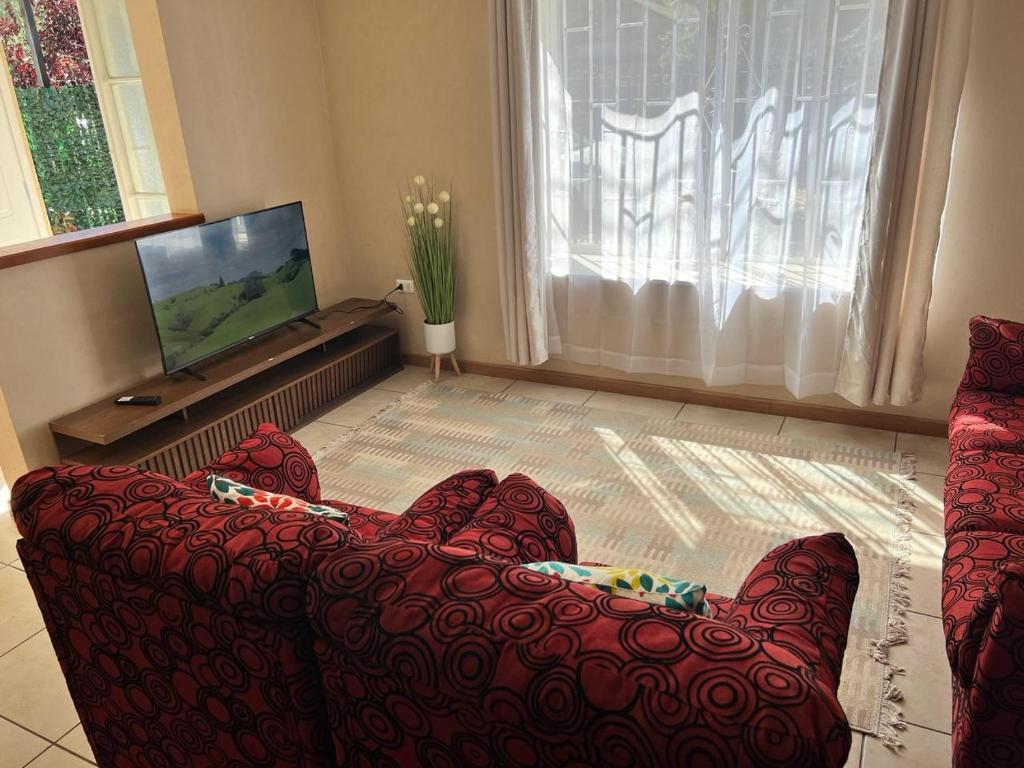 sala de estar con sofá rojo y TV de pantalla plana en Amplia Casa 8 dormitorios 4 baños Avenida Lircay, en Talca