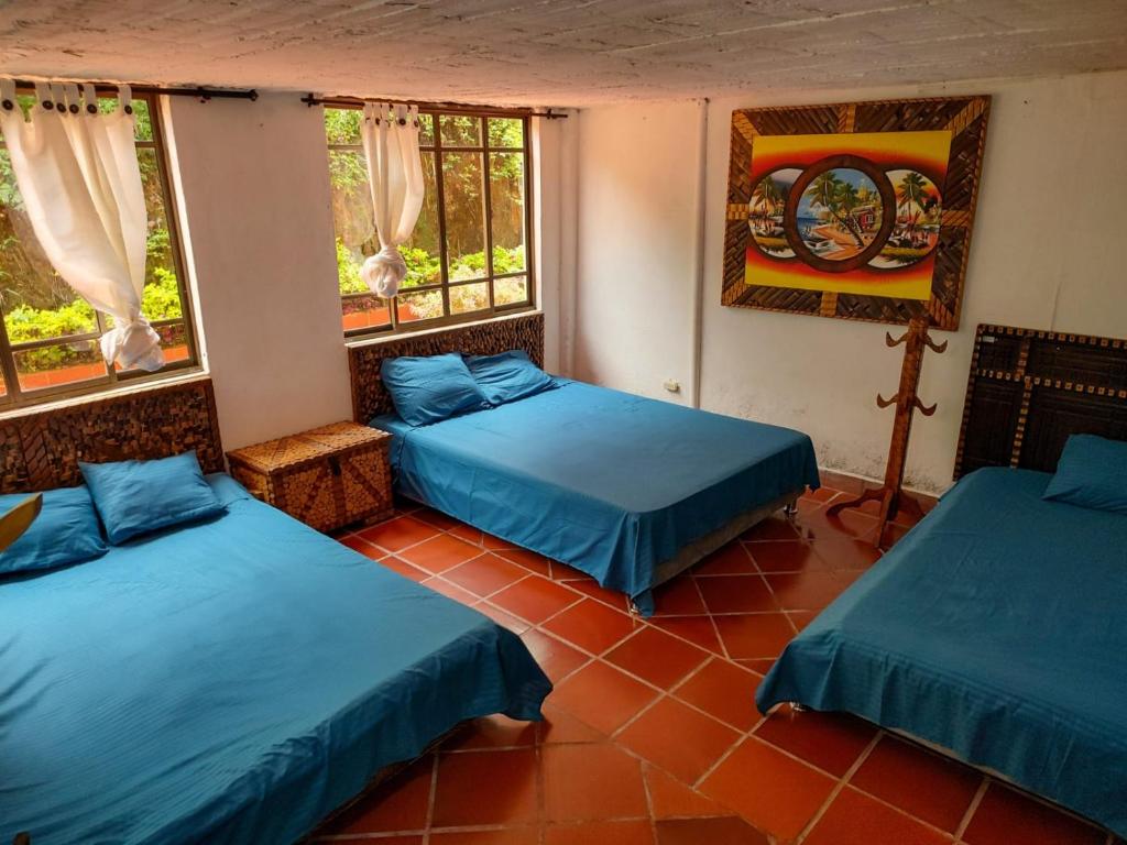 a room with three beds and two windows at Hacienda la riviera in Santa Rosa de Cabal