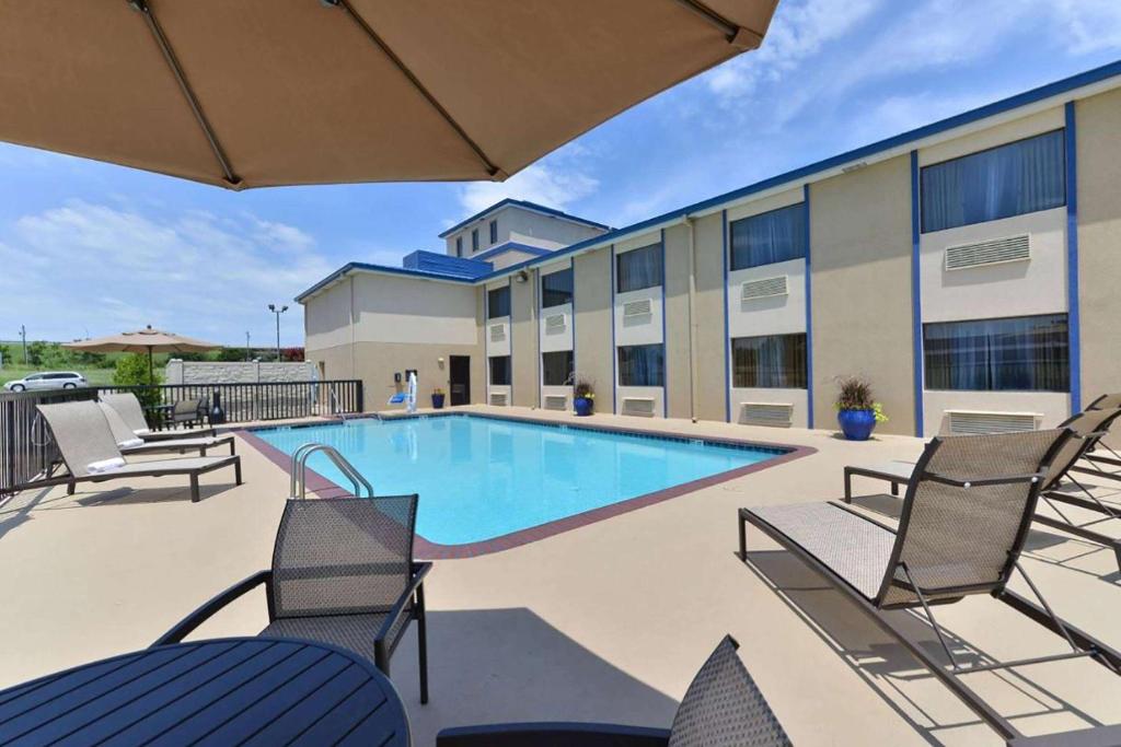 una piscina con sillas, una mesa y un edificio en Baymont by Wyndham Ardmore I-35 en Ardmore