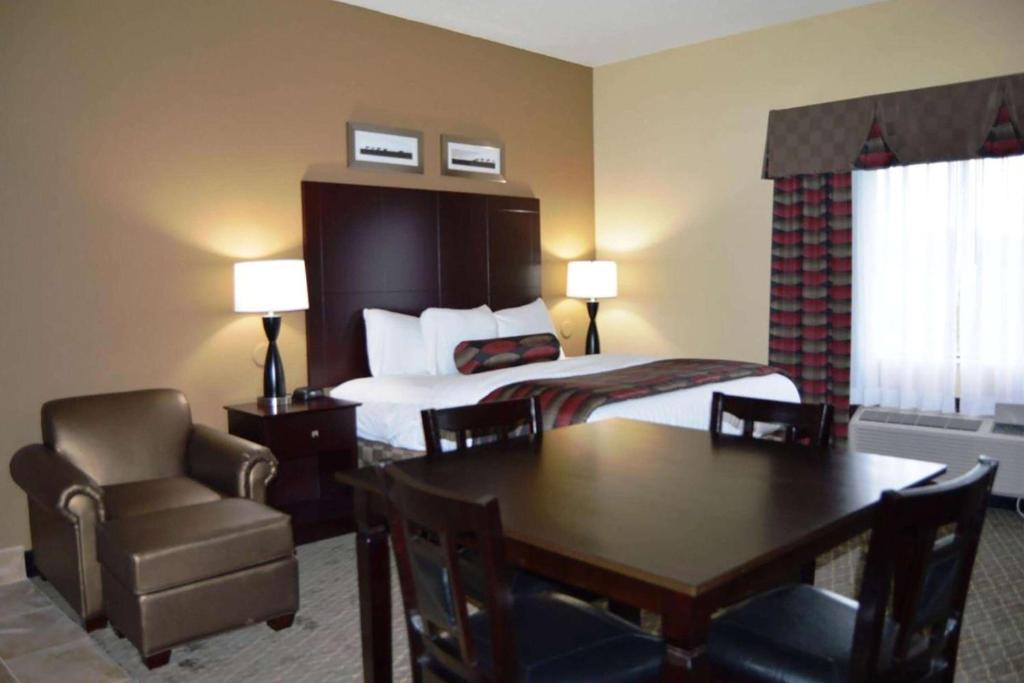 a hotel room with a bed and a table and chair at Baymont by Wyndham Ardmore I-35 in Ardmore