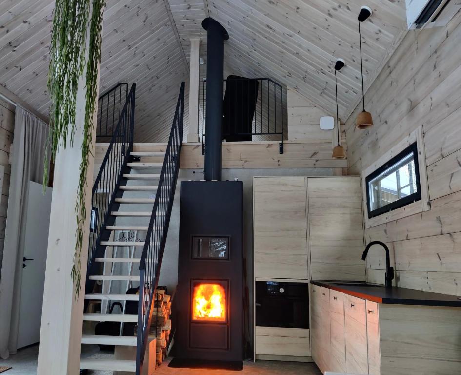 米凯利Moderni vierasmökki的一间厨房中间的壁炉,厨房设有楼梯