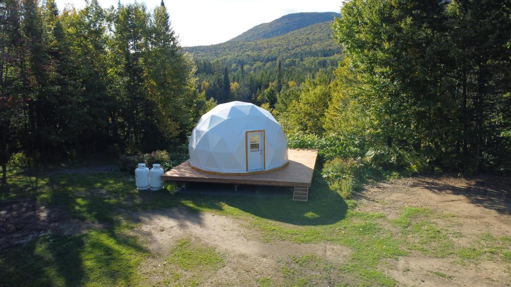 une tente blanche sur une plate-forme en bois dans un champ dans l'établissement Vallée Jeunesse Québec, à Saint-Gabriel-de-Valcartier