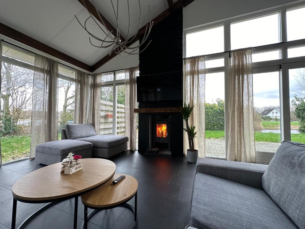een woonkamer met een bank, een tafel en een open haard bij Groot vakantiehuis nabij Amsterdam inclusief jacuzzi in Zeewolde