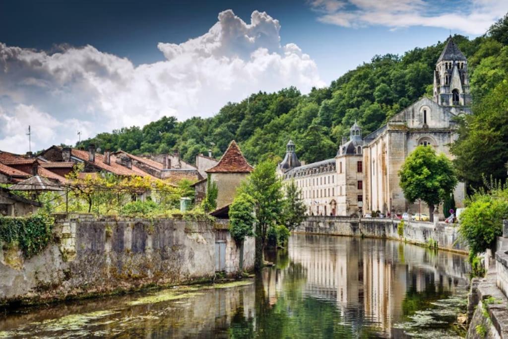 a city with a river and buildings and a church at Appartement Cosy centre-ville in Ribérac