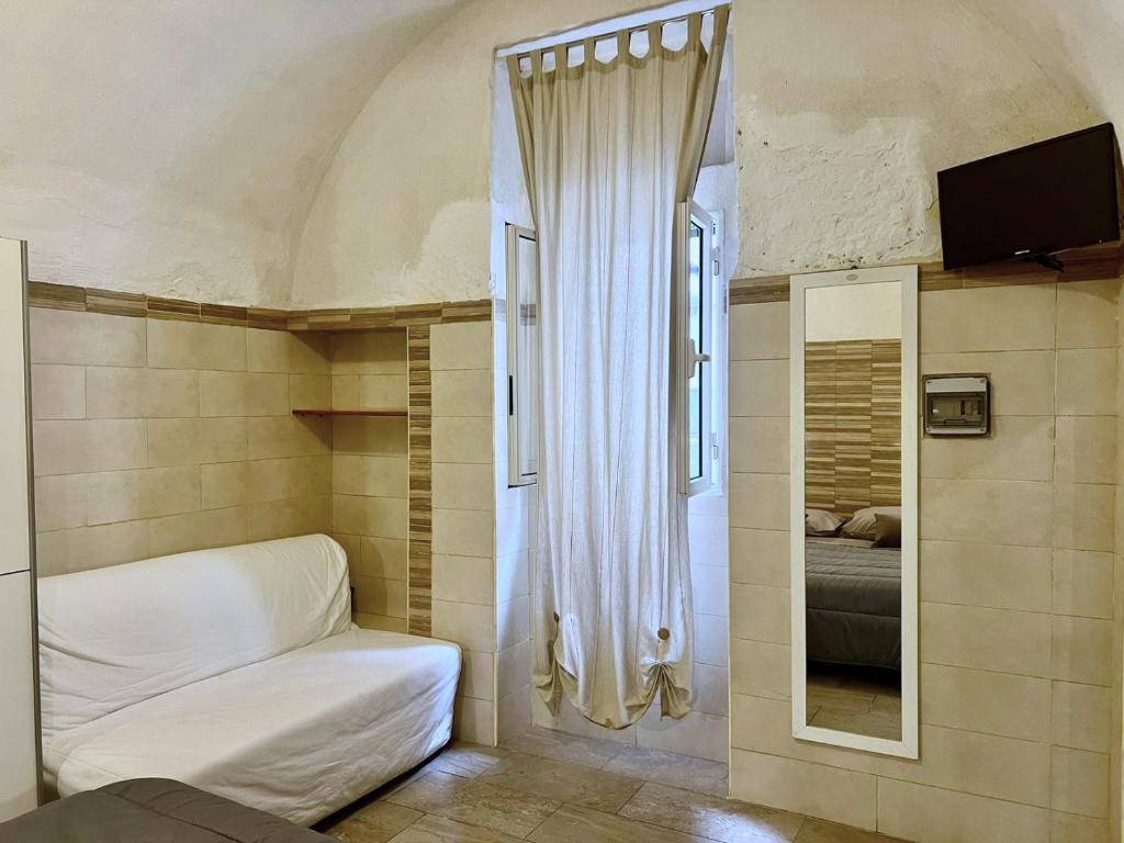 mały pokój z łóżkiem i lustrem w obiekcie Casa Monopoli w mieście Monopoli