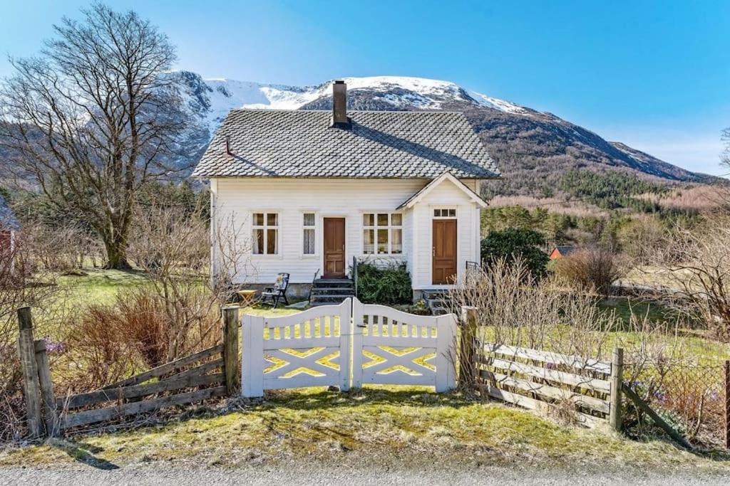 una casa blanca con una valla y una montaña en Gammelt hus på landet, 