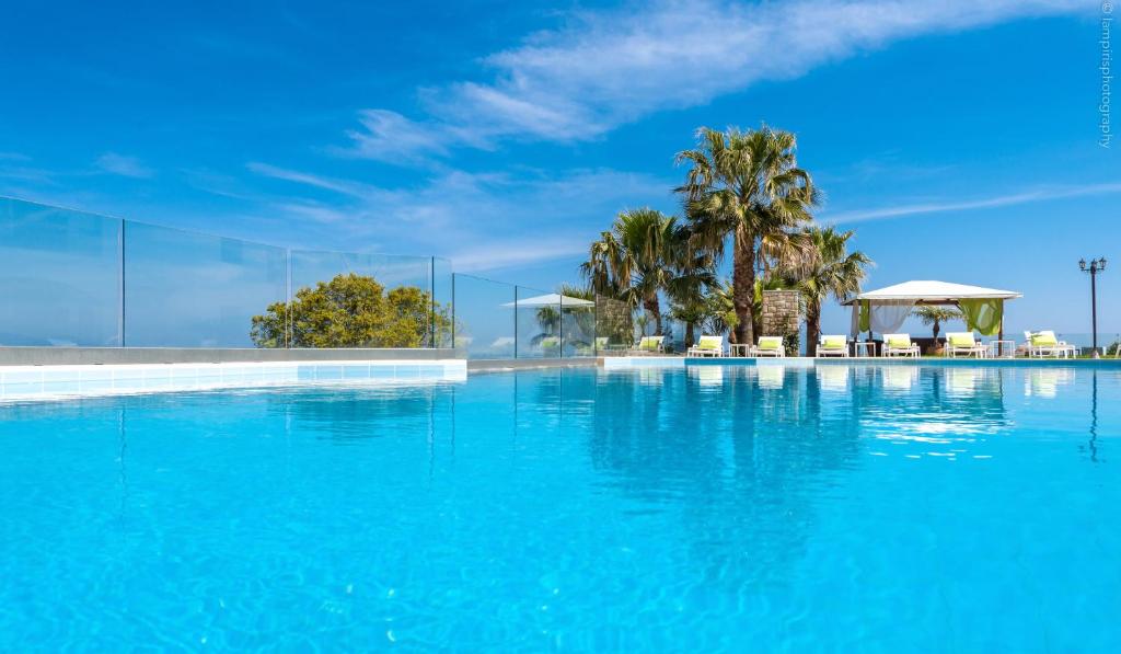 a swimming pool with blue water and palm trees at Erietta Apartments in Tsilivi