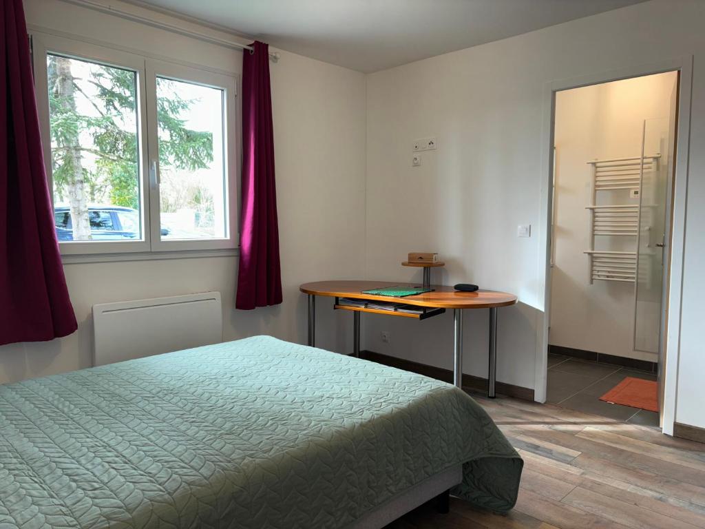 a bedroom with a bed and a table and window at Les clés de jonzac-conciergerie la maison des 4 Saisons in Ozillac