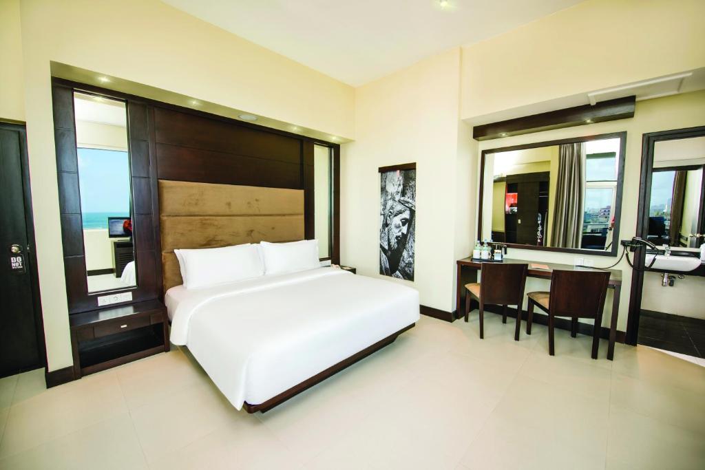 Un dormitorio con una gran cama blanca y una mesa en Fair View Hotel Colombo, en Colombo