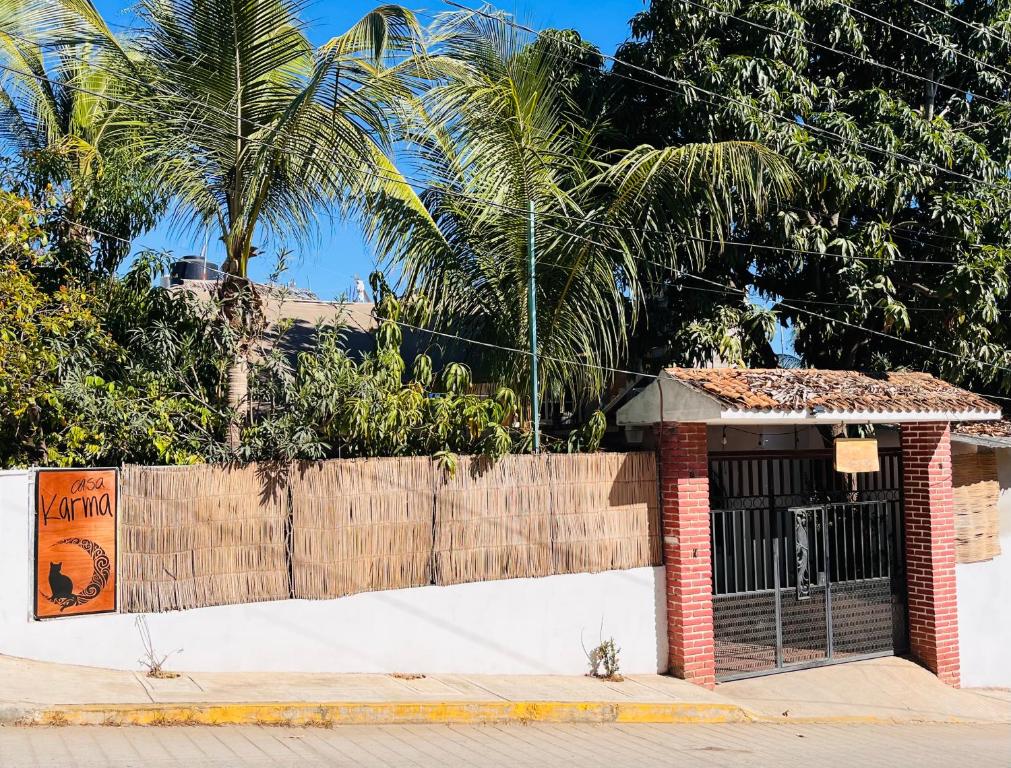 a gate on a building with a fence and palm trees at Casa Karma in Puerto Escondido