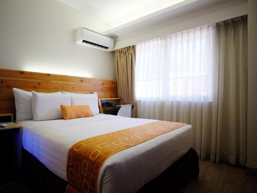 a hotel room with a large bed and a window at Cuarto Hotels Cebu in Cebu City