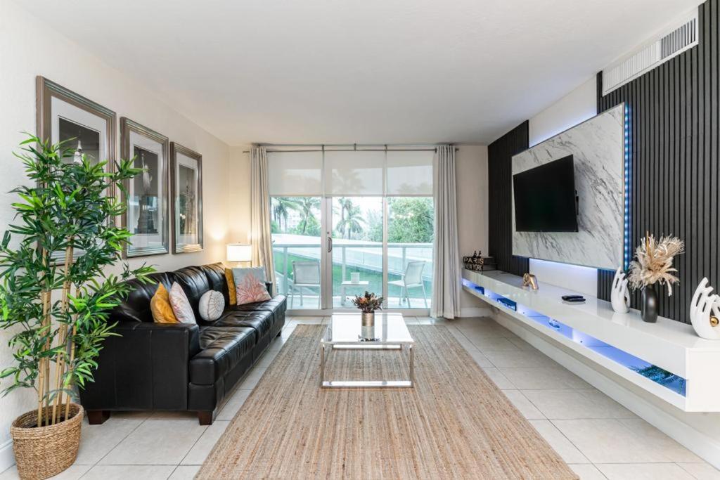 ein Wohnzimmer mit einem schwarzen Sofa und einem TV in der Unterkunft Beachfront Modern 5 Stars 1 Bedroom Apartment in Hollywood