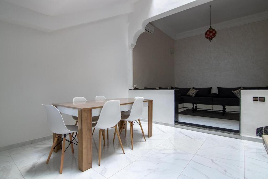 una sala da pranzo con tavolo e sedie bianche di RIAD TAWSALANE a Marrakech