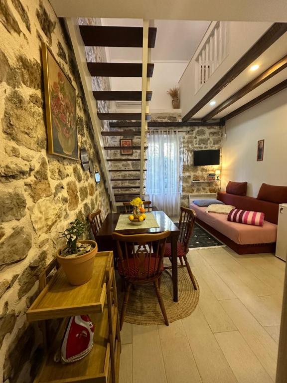 ein Wohnzimmer mit einem Tisch und einer Steinmauer in der Unterkunft Etno village Mihailovic II in Herceg-Novi