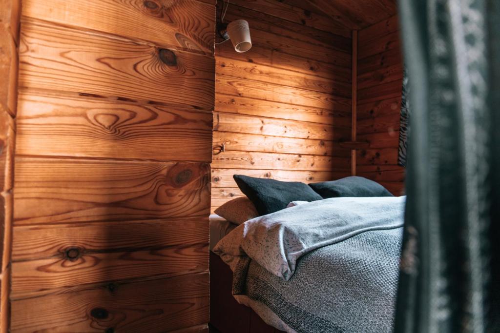a bedroom with wooden walls and a bed in a room at Kaldbaks-kot cottages in Húsavík