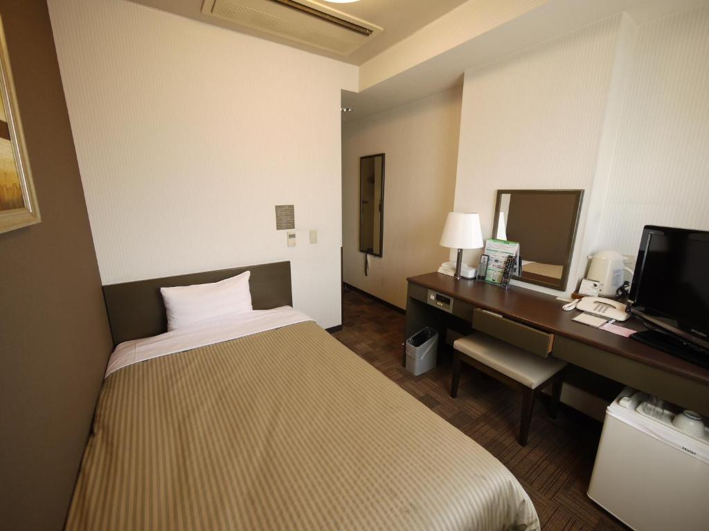 上野原市にあるホテルルートインコート上野原のベッド、デスク、テレビが備わるホテルルームです。