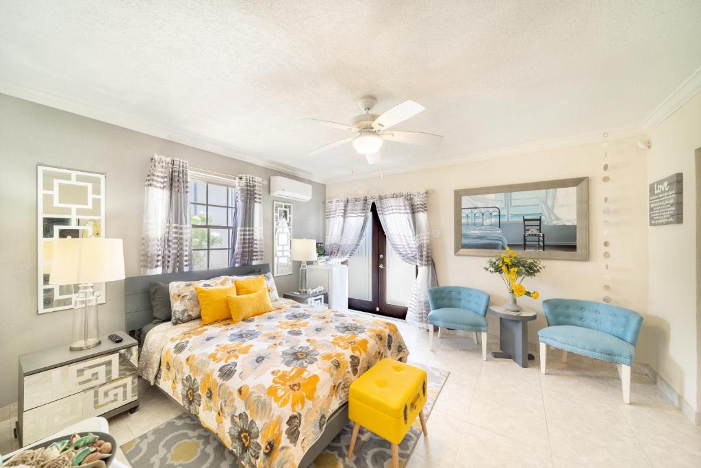 a bedroom with a bed and two blue chairs at Hidden Gem Barbados in Christ Church
