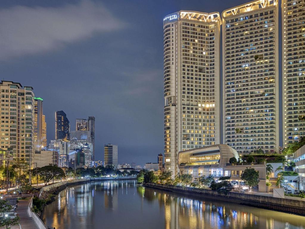a city with tall buildings and a river at night at Novotel Suites Manila at Acqua in Manila
