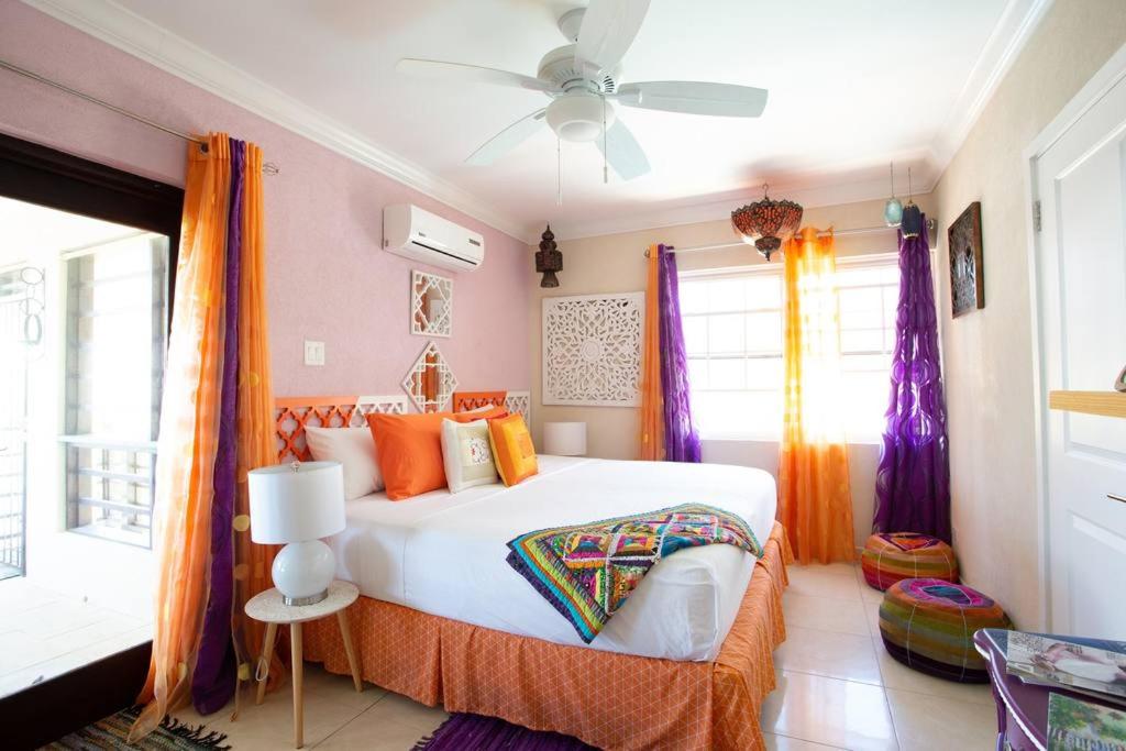 a bedroom with a large bed with orange curtains at Hidden Gem Barbados in Christ Church