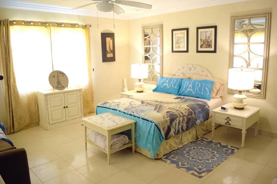a bedroom with a bed and two tables and two lamps at Hidden Gem Barbados in Christ Church