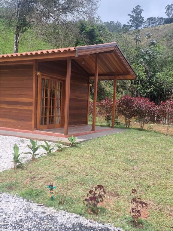 a small cabin with a porch in a yard at Chalé Pavão Recanto Buscapé SFX in São Francisco Xavier