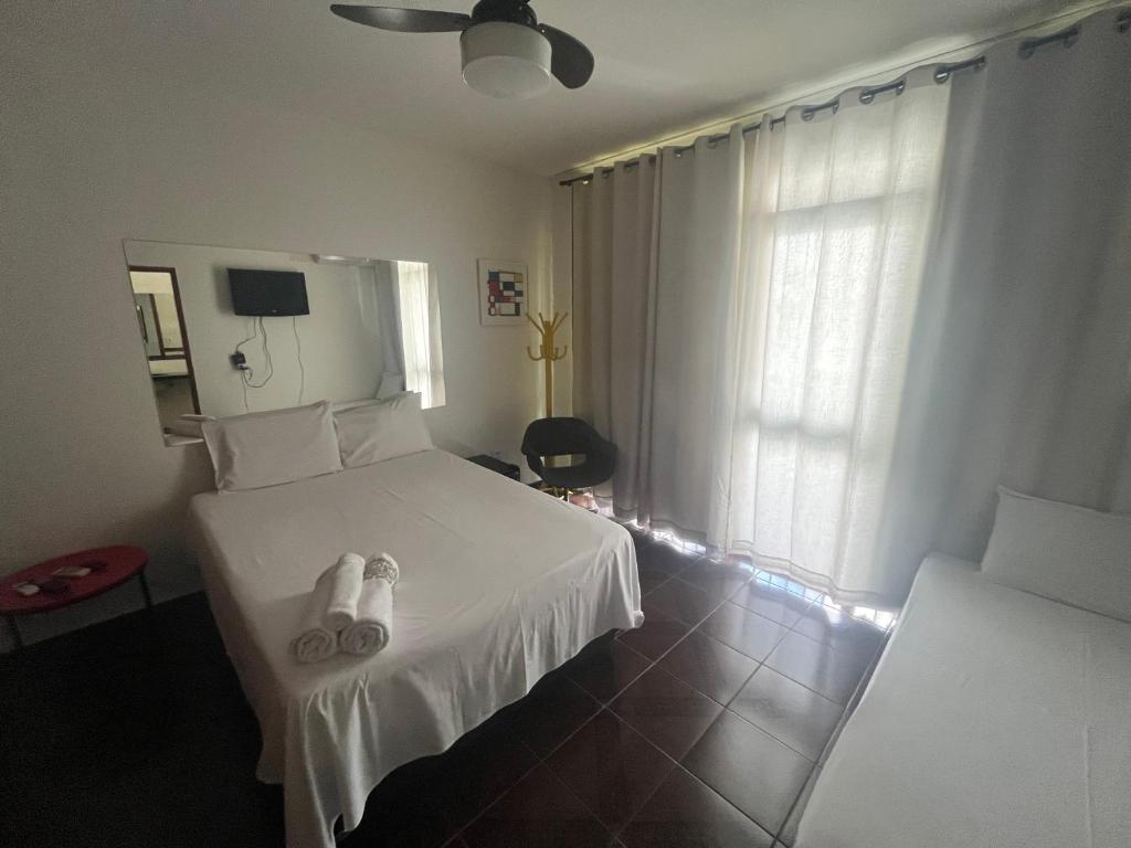 Un dormitorio con una cama blanca con zapatillas. en Suíte completa no Bueno Somente para mulheres en Goiânia