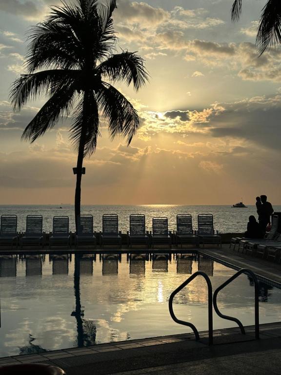 un hombre sentado bajo una palmera junto a una piscina en Seafront38&39 - Regency Tg Tuan beach resort, port dickson en Port Dickson