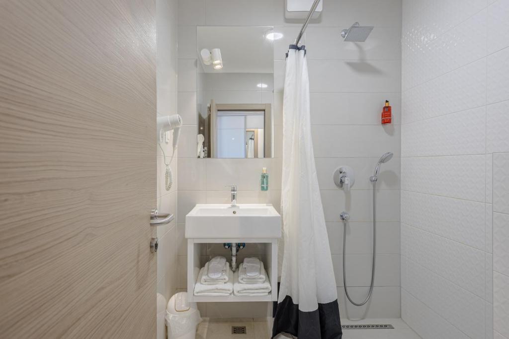 a white bathroom with a sink and a shower at Rogač Rooms & Restaurant in Omiš