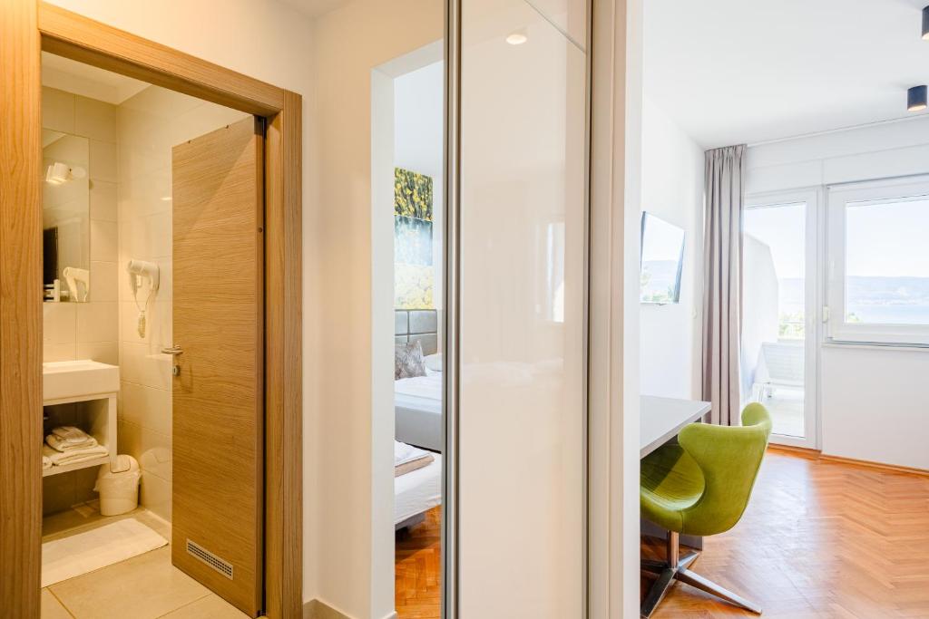 a bathroom with a green chair in front of a door at Rogač Rooms & Restaurant in Omiš