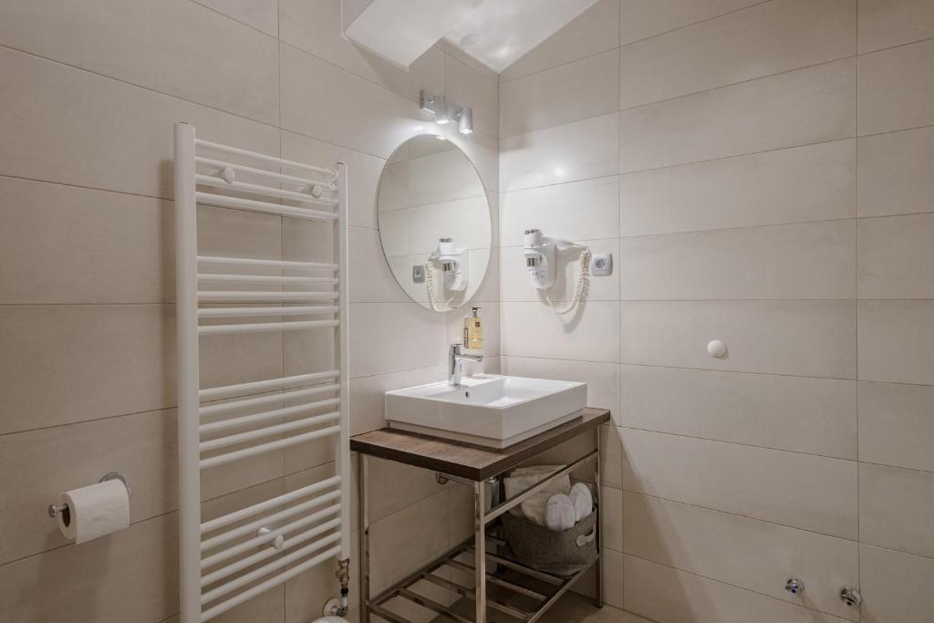 a white bathroom with a sink and a mirror at Rogač Rooms & Restaurant in Omiš