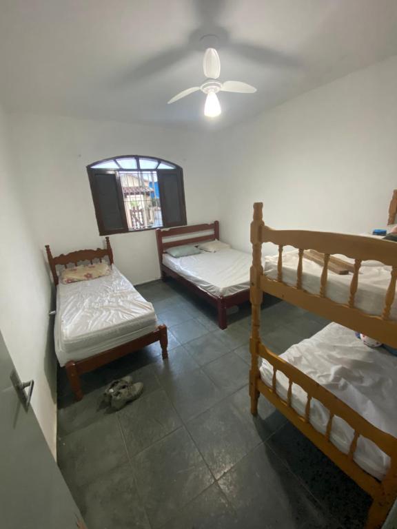 a room with three bunk beds and a ceiling at Casa na praia, 15 min de caminhada in Itanhaém