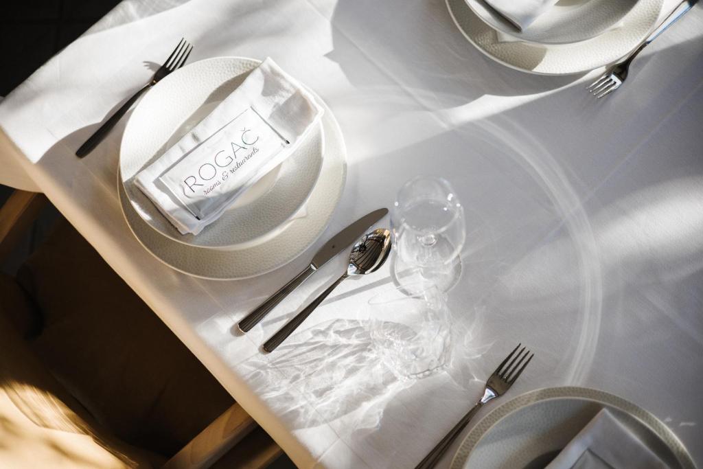 a white table with plates and silverware on it at Rogač Rooms & Restaurant in Omiš