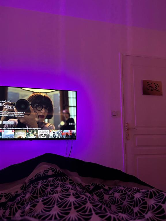 a bedroom with a purple wall with a tv at Très jolie F2 cosy 45m2 avec balcon et parking proche Paris in Livry-Gargan