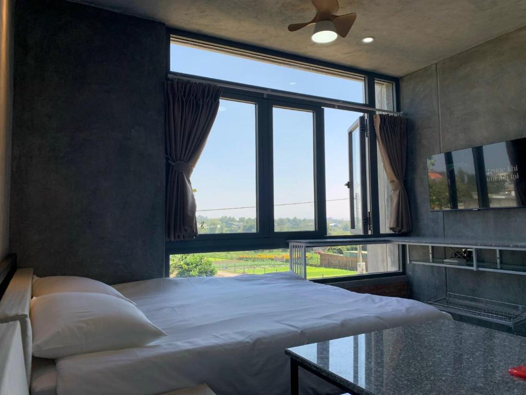 ein Schlafzimmer mit einem Bett und einem großen Fenster in der Unterkunft miniHomestay green view - single room - AC and bathtub - Ea Kar - Dak Lak in Buôn Mhang