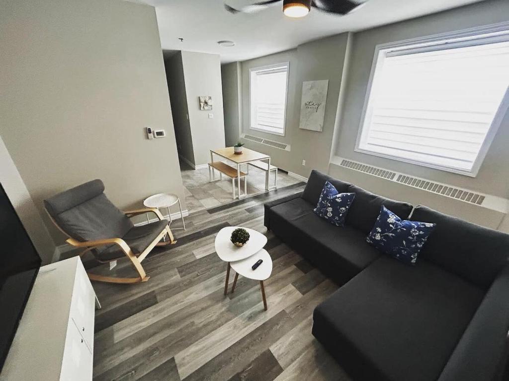 a living room with a black couch and a table at Premium 2-bed Condo Uptown Saint John Parking Coffee Location in Saint John