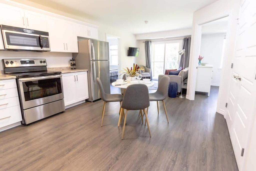 a kitchen and dining room with a table and chairs at Brand new Gorgeous Condo Near UNB & Hospital Coffee Parking 202 in Saint John