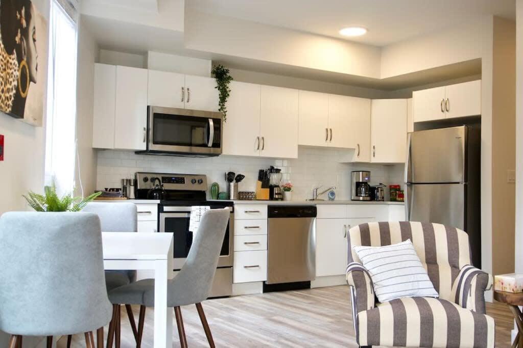 - une cuisine avec des placards blancs, une table et des chaises dans l'établissement Premium Modern Condo Top Location 2Bed, à Winnipeg