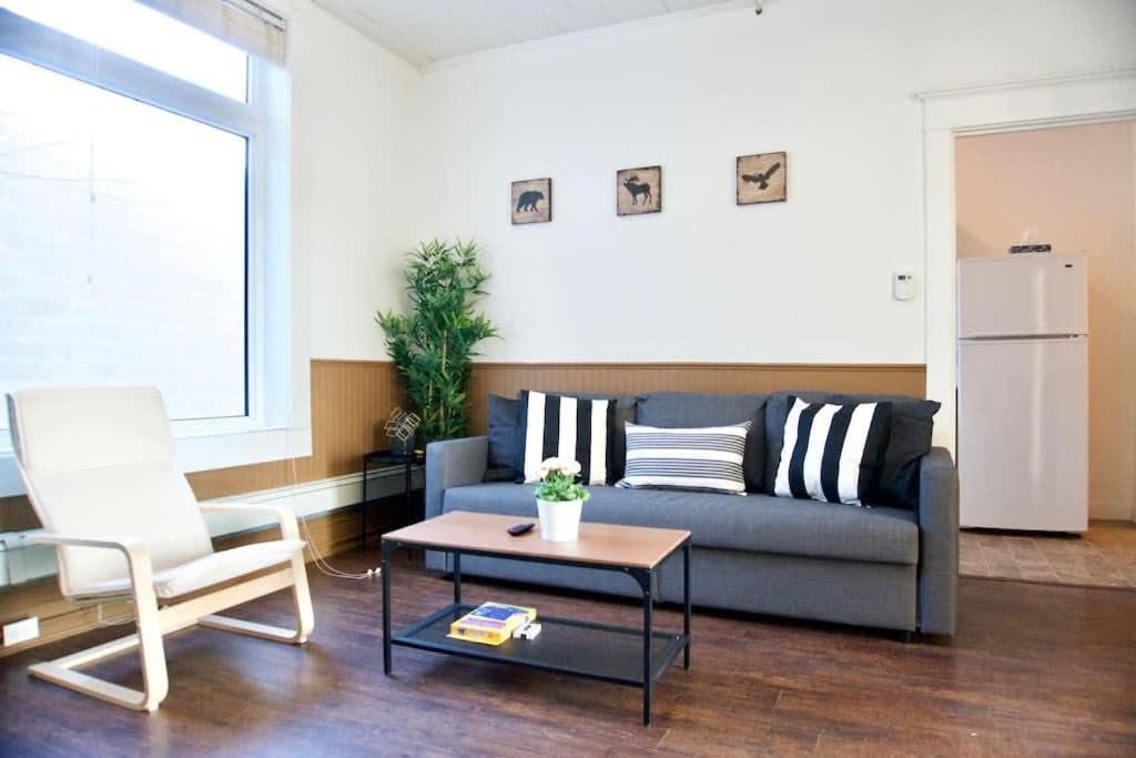 ein Wohnzimmer mit einem Sofa, einem Tisch und einem Stuhl in der Unterkunft NEW Stunning Large Gorgeous Space Downtown Parking Coffee in Moose Jaw