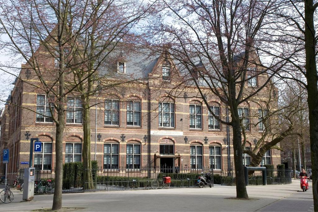 un gran edificio de ladrillo con árboles delante de él en The College Hotel Amsterdam, Autograph Collection, en Ámsterdam